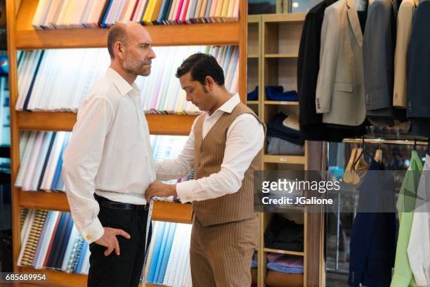 man krijgt gemeten voor een op maat gemaakte pak in een winkel van de kleermaker - made to measure fashion stockfoto's en -beelden