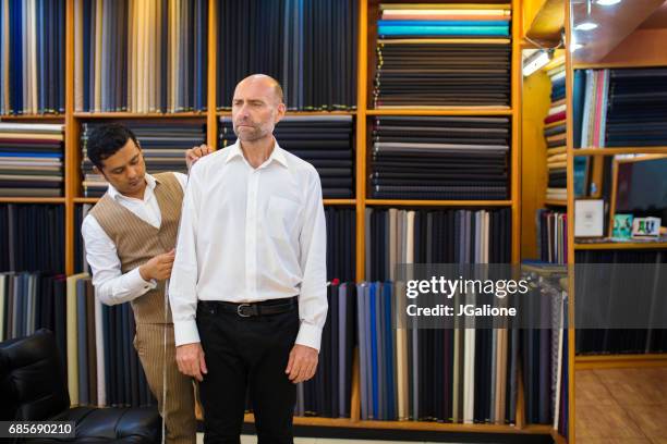 man krijgt gemeten voor een op maat gemaakte pak in een winkel van de kleermaker - made to measure fashion stockfoto's en -beelden