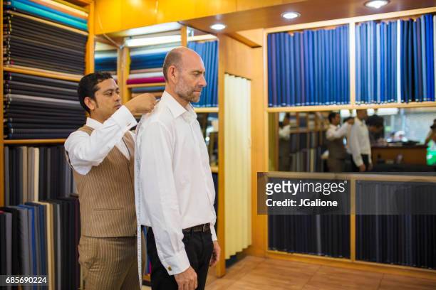 man krijgt gemeten voor een op maat gemaakte pak in een winkel van de kleermaker - made to measure fashion stockfoto's en -beelden