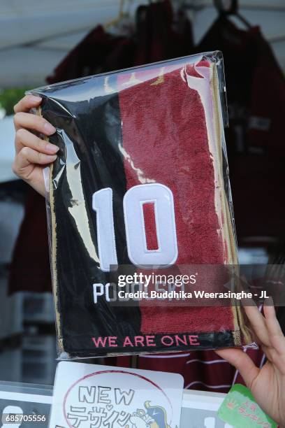 Shop assistant holds a scard of Lucas Podolski, who is joining Vissel Kobe, at a marchandise stall prior to the J.League J1 match between Vissel Kobe...