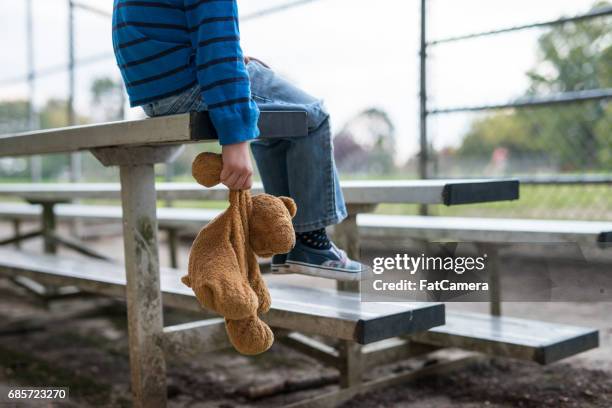 jeune garçon assis seul sur les gradins. - ours en peluche photos et images de collection