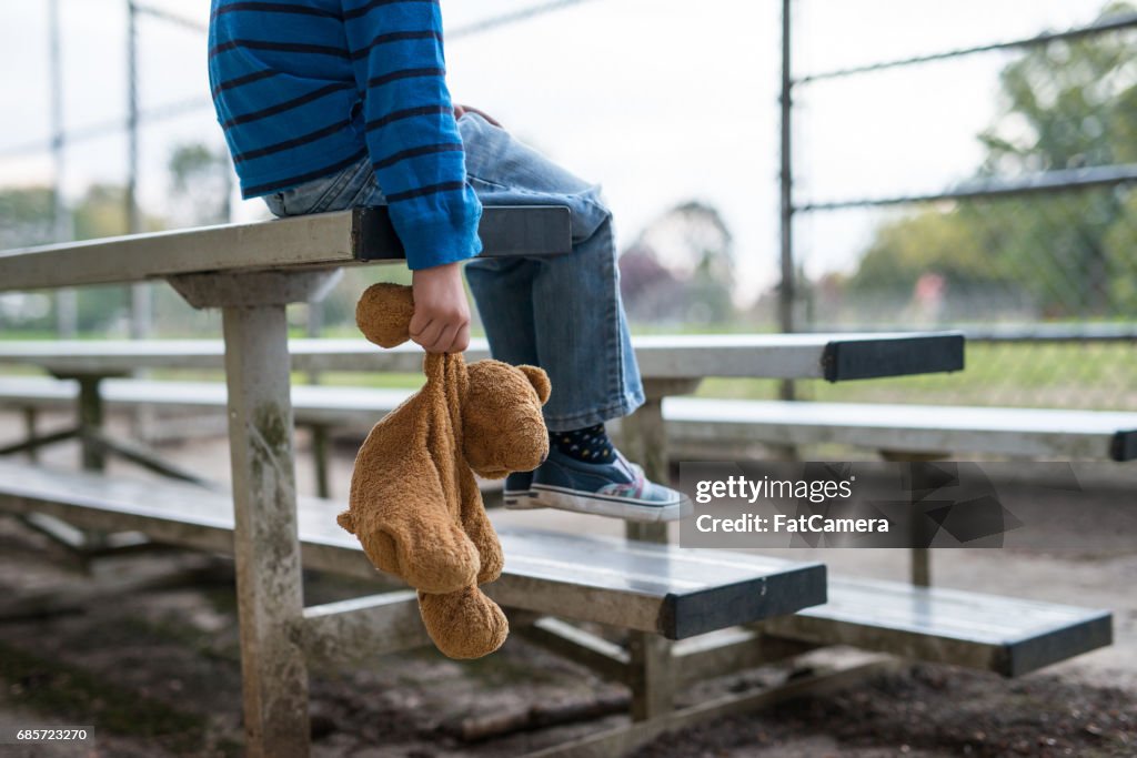 Young boy sitting by himself on on bleachers.