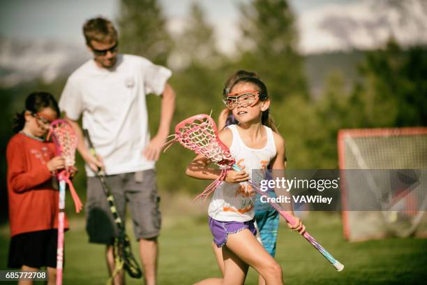 chica jugando lacrosse con papá y amigos - lacrosse fotografías e imágenes de stock