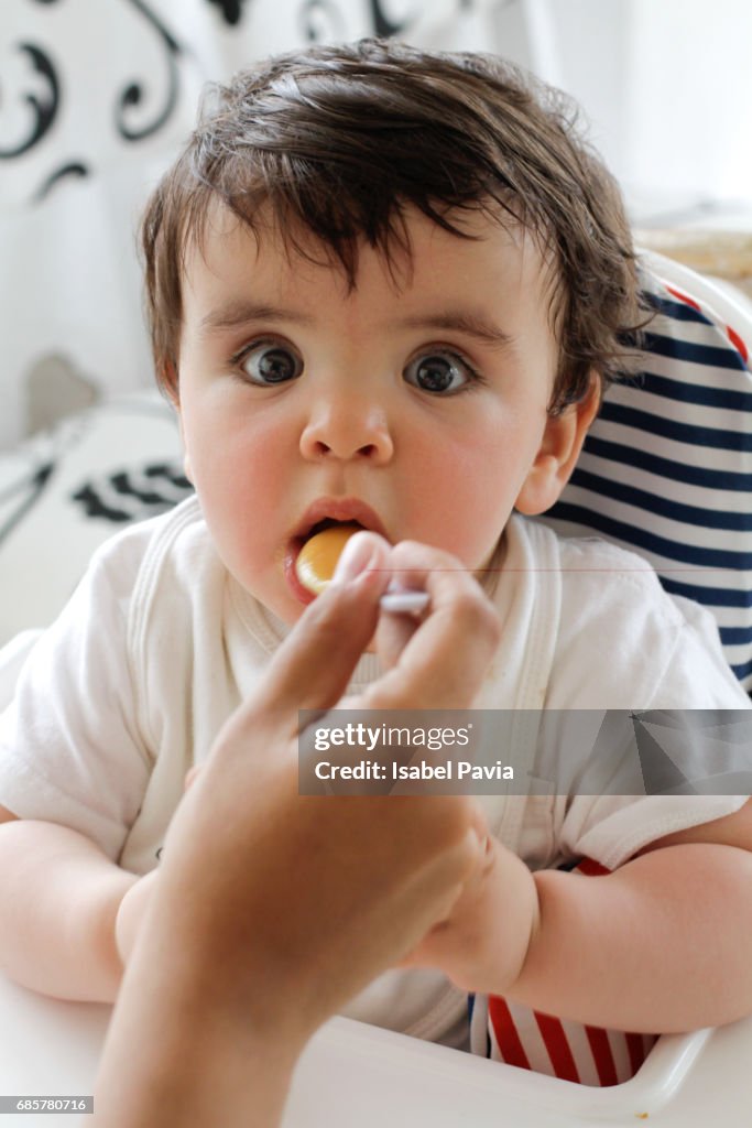 Mother feeding baby in highchair