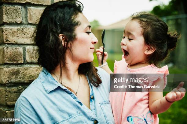 Excited young girl being held by mother during backyard birthday party