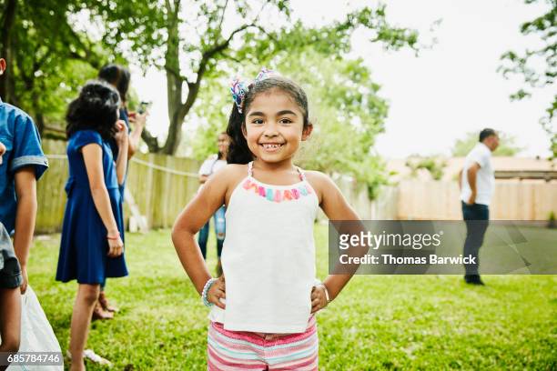Smiling young girl standing in backyard during family birthday party