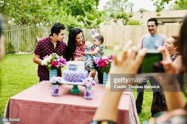 family celebrating first birthday for young girl in backyard - eerste verjaardag stockfoto's en -beelden