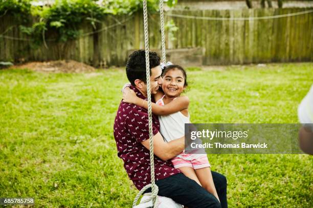 laughing young girl swinging on swing with uncle during family party - niece 個照片及圖片檔