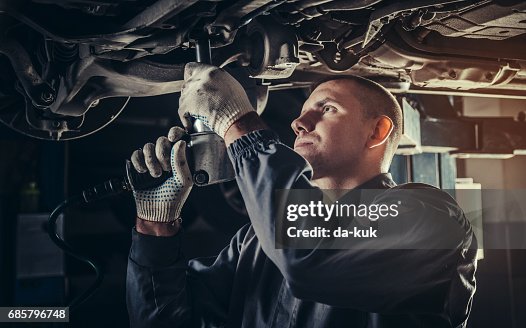 Professional mechanic repairing a car in auto repair shop Professional mechanic repairing a car in auto repair shop