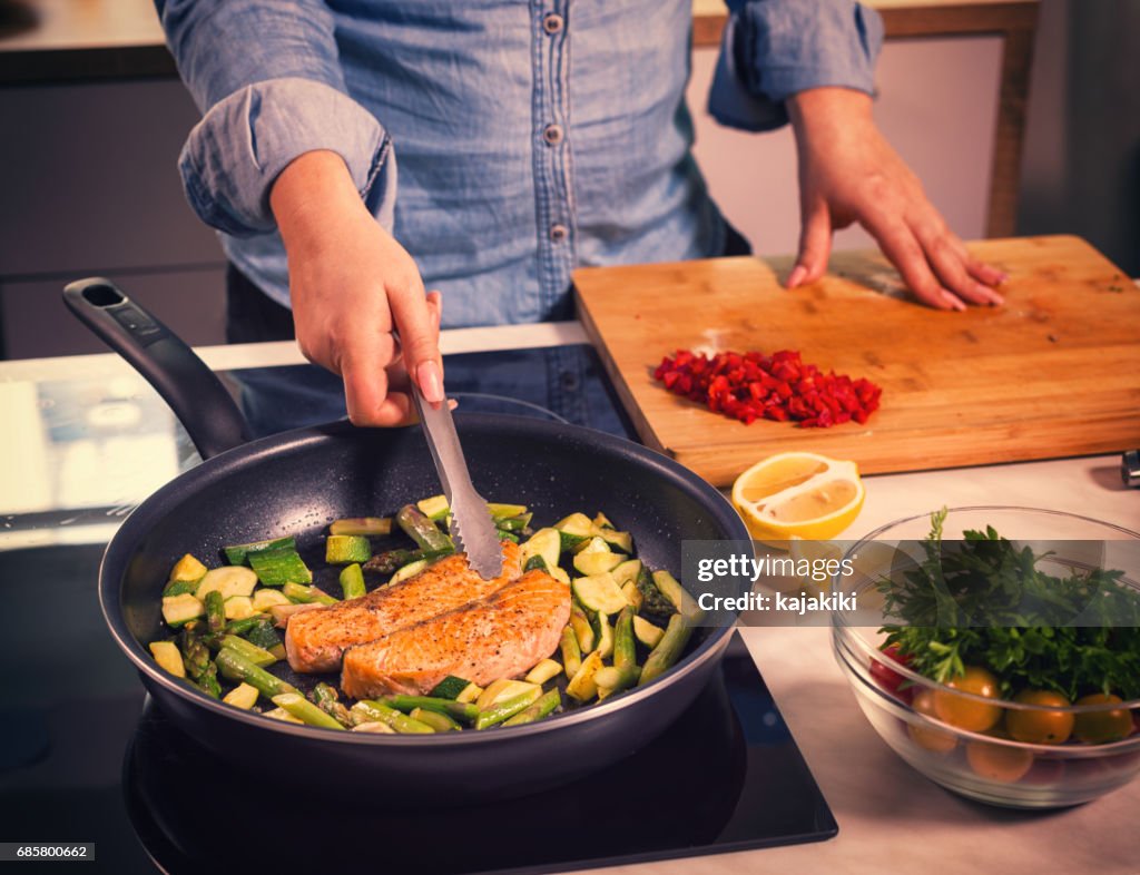 Mujeres jóvenes preparar salmón en casa
