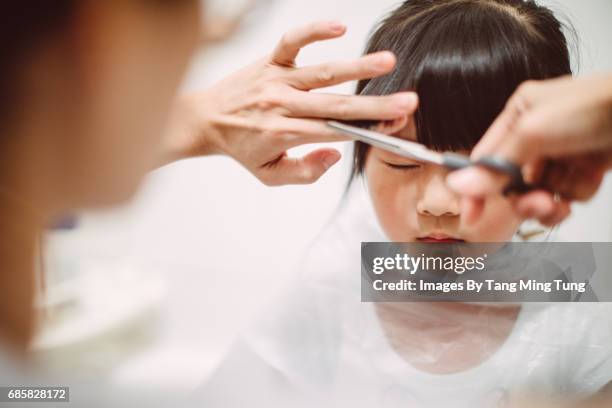 Mom cutting lovely little daughter's hair