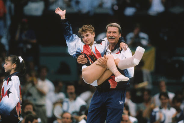 Kerri Strug of the United States is carried by coach Bela Karolyi during the team competition of the Women's Gymnastics event of the 1996 Summer...