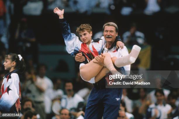 Kerri Strug of the United States is carried by coach Bela Karolyi during the team competition of the Women's Gymnastics event of the 1996 Summer...