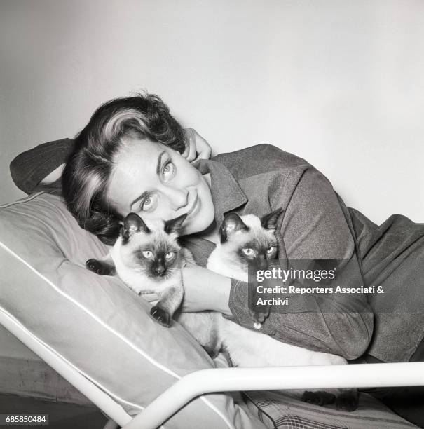 Italian actress Alida Valli cuddling cats in her house. 1957