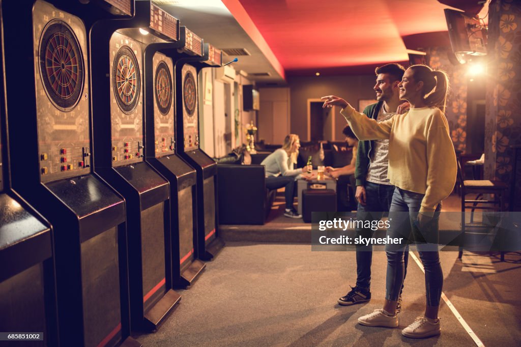 Junge glückliche Paar spielen Dart im Entertainment Club.