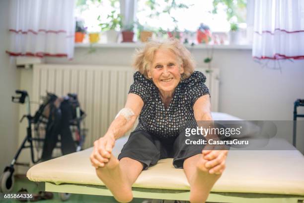 over 90 senior woman take care of her body by doing streching exercises - touching toes stock pictures, royalty-free photos & images