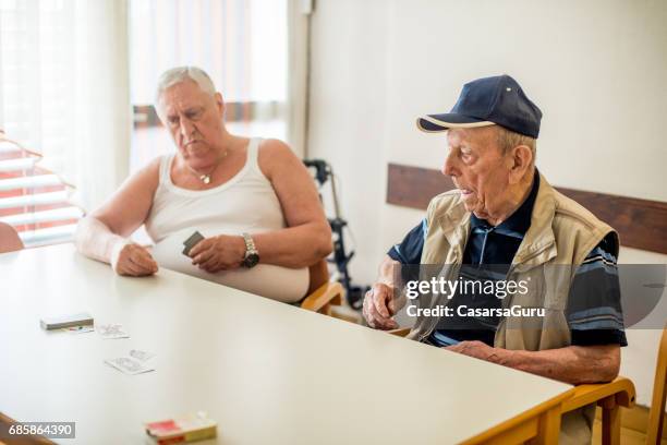 senior mannen speelkaart voor ontspanning in het verpleeghuis - alleen seniore mannen stockfoto's en -beelden