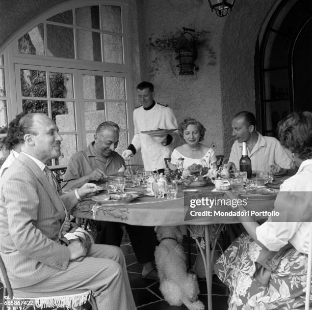 Italian publisher Arnoldo Mondadori and his wife Andreina Monicelli sitting at the table with some friends. Left to right, Guido Piovene , his wife...