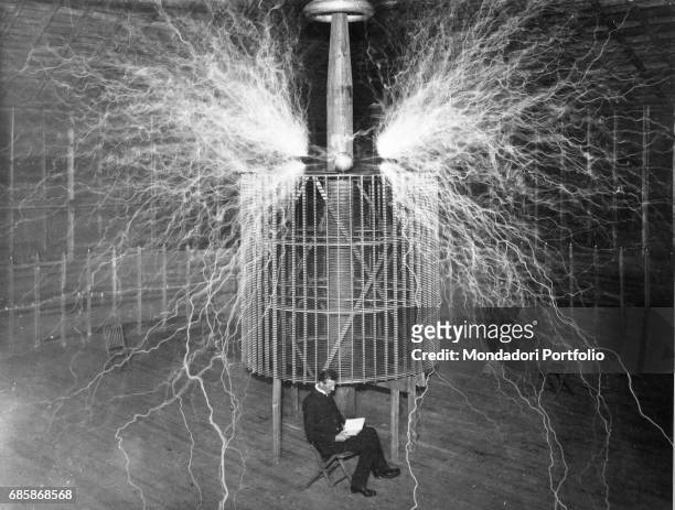 Nikola Tesla , Serbian-American physicist sitting in his Colorado Springs laboratory with his "Magnifying transmitter" - 1899