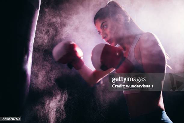 junge frau mit boxhandschuhen und einen boxsack training - boxing coach stock-fotos und bilder