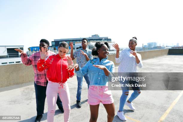 Teenagers dancing on a London rooftop overlooking the city.