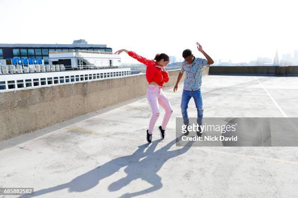 Teenagers dancing on a London rooftop overlooking the city.