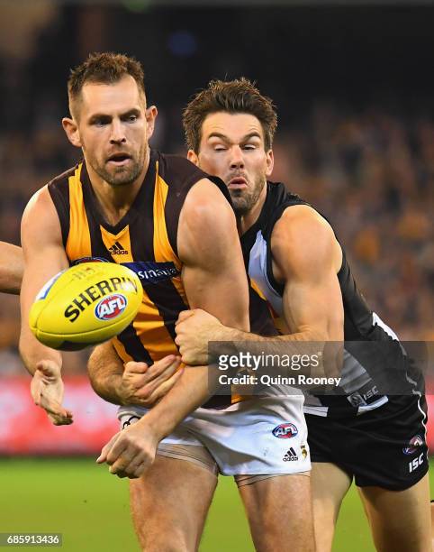 Luke Hodge of the Hawks handballs whilst being tackled by Levi Greenwood of the Magpies during the round nine AFL match between the Collingwood...