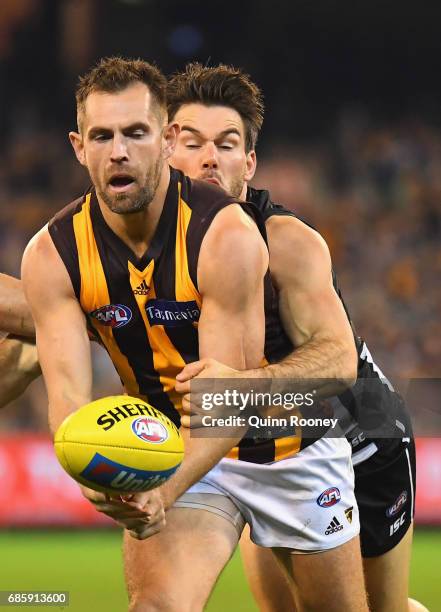Luke Hodge of the Hawks handballs whilst being tackled by Levi Greenwood of the Magpies during the round nine AFL match between the Collingwood...