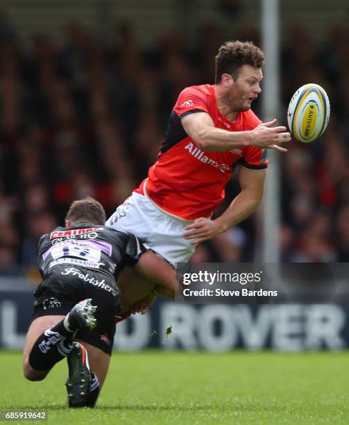 Duncan Taylor of Saracens offloads as he is tackled by Ollie Devoto of Exeter Chiefs during the Aviva Premiership semi final match between Exeter...