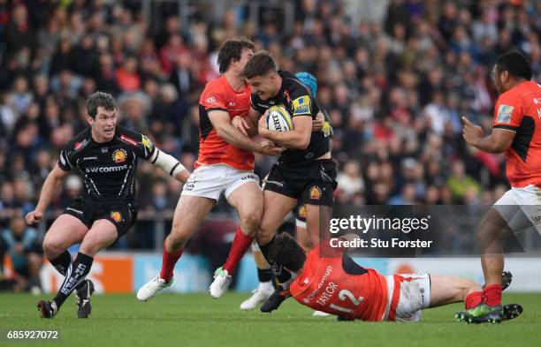 Ollie Devoto of Exeter Chiefs is tackled by Marcelo Bosch and Duncan Taylor of Saracens during the Aviva Premiership semi final match between Exeter...