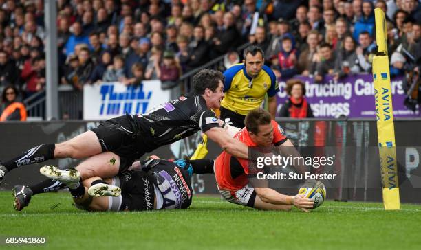 Chris Wyles of Saracens dives past the tackles from Jack Nowell and Ian Whitten of Exeter Chiefs to score his team's first try during the Aviva...