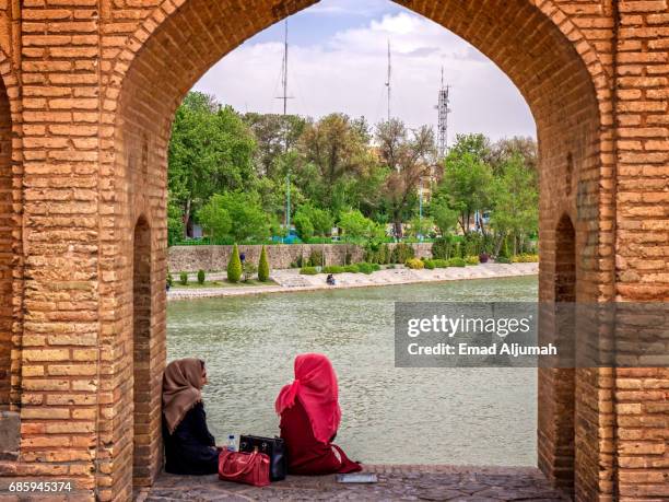 two giril siting under si-o-seh pol (the bridge of thirty-three spans), isfahan, iran - 26 april 2017 - si o seh stock pictures, royalty-free photos & images