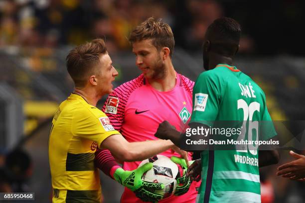Marco Reus of Borussia Dortmund attempts to take the ball off Felix Wiedwald of Werder Bremen after scoring his teams third goal of the game during...