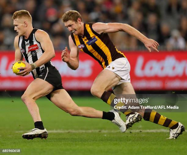 Adam Treloar of the Magpies runs ahead of Ben McEvoy of the Hawks during the 2017 AFL round 09 match between the Collingwood Magpies and the Hawthorn...