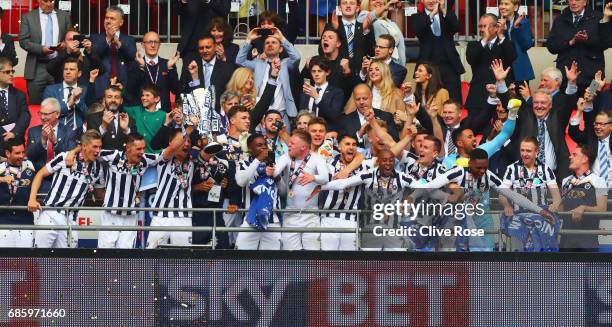 Captain Tony Craig of Millwall lifts the trophy as he celebrates victory and promotion with team mates after the Sky Bet League One Playoff Final...