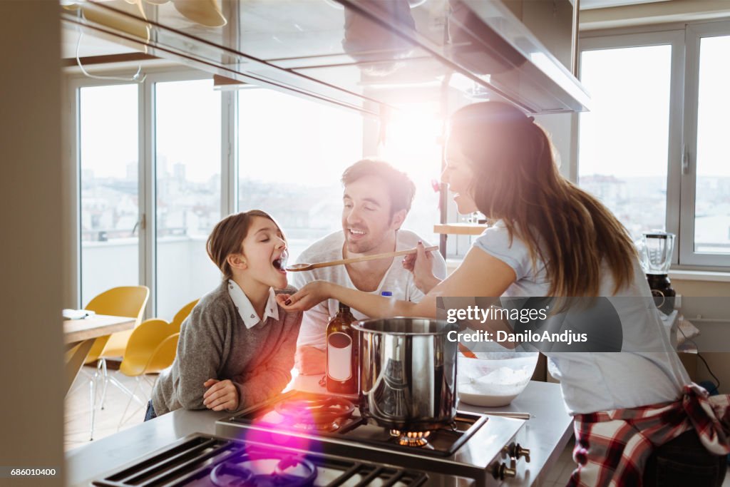 Mother cooking and giving her daughter to try