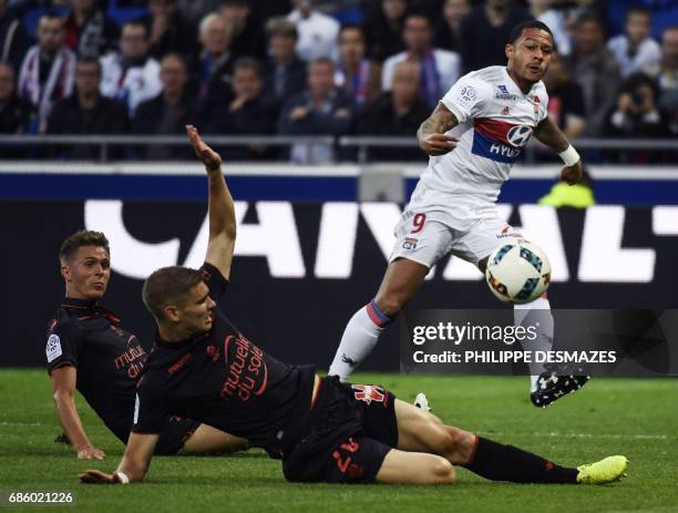 Lyon's Dutch forward Memphis Depay shoots and scores past Nice's French defender Arnaud Souquet and Nice's French defender Maxime Le Marchand during...