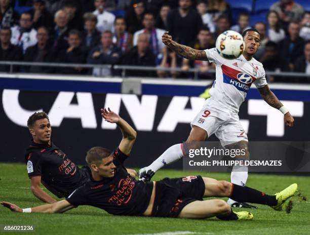 Lyon's Dutch forward Memphis Depay shoots and scores past Nice's French defender Arnaud Souquet and Nice's French defender Maxime Le Marchand during...