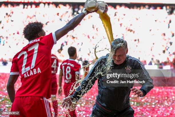 David Alaba of FC Bayern Muenchen and Carlo Ancelotti, head coach of FC Bayern Muenchen celebrates with beer after the Bundesliga match between...