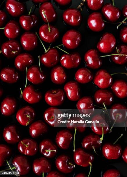 red cherries on black background - black cherries stock-fotos und bilder