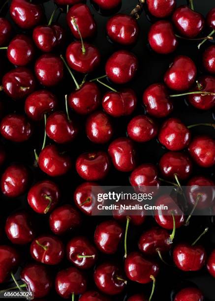 red cherries on black background - cherry stock pictures, royalty-free photos & images
