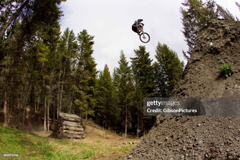 A young man hits a big jump on his downhill-style mountain bike.