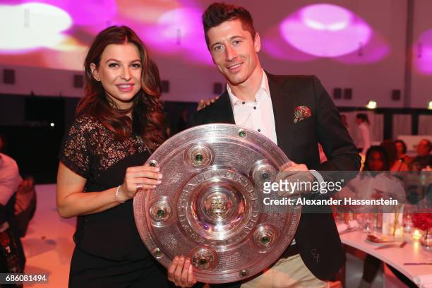 Robert Lewandowski and his wife Anna Stachurska pose with the trophy during the FC Bayern Muenchen Championship party following the Bundesliga match...