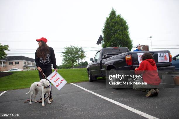 An activist with a puppy prepares to affix her car with a protest posters against the Klu Klux Klan before driving in a caravan through the...