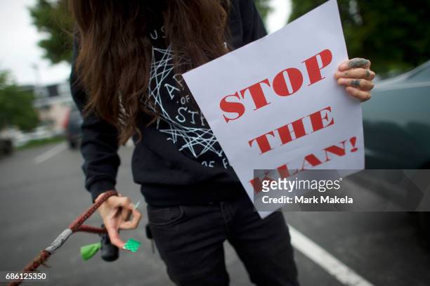 An activist with a puppy prepares to affix her car with a protest poster against the Klu Klux Klan before driving in a caravan through the...