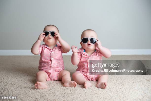 11 month old fraternal twin boys play together with sunglasses - fraternal twin stock pictures, royalty-free photos & images