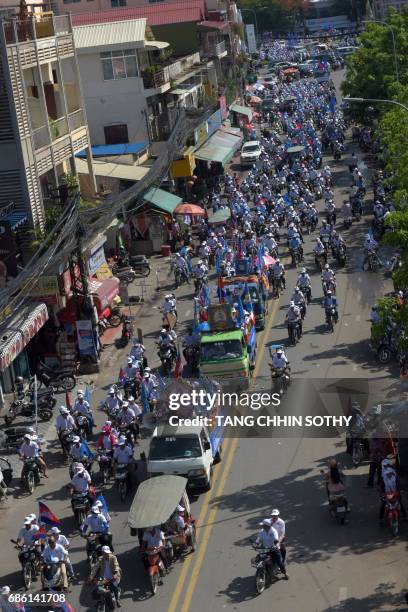 Supporters of Cambodian People Party march during the Commune Election Campaign in Phnom Penh on May 21, 2017. Tuk-tuks blaring pop music and...