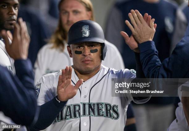Carlos Ruiz of the Seattle Mariners is congratulated by teammates in the dugout after scoring a run on a ground out by Jean Segura of the Seattle...