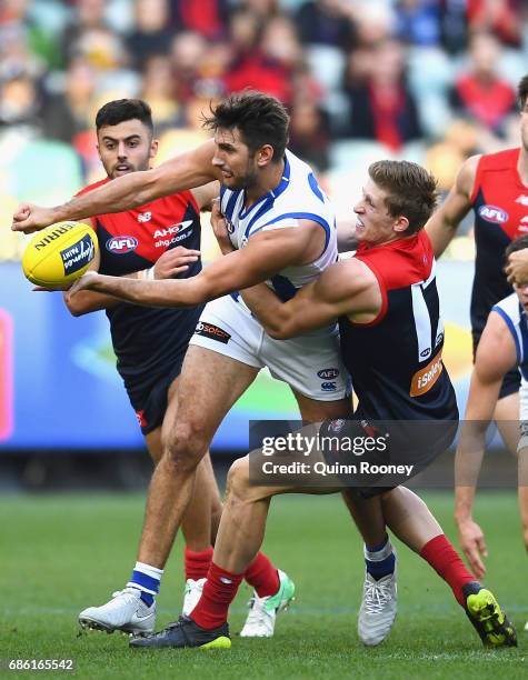 Jarrad Waite of the Kangaroos handballs whilst being tackled Sam Frost of the Demons during the round nine AFL match between the Melbourne Demons and...