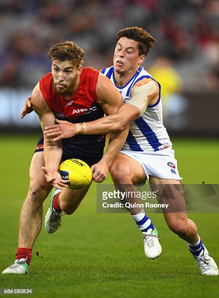 Jack Viney of the Demons handballs whilst being tackled by Nathan Hrovat of the Kangaroos during the round nine AFL match between the Melbourne...